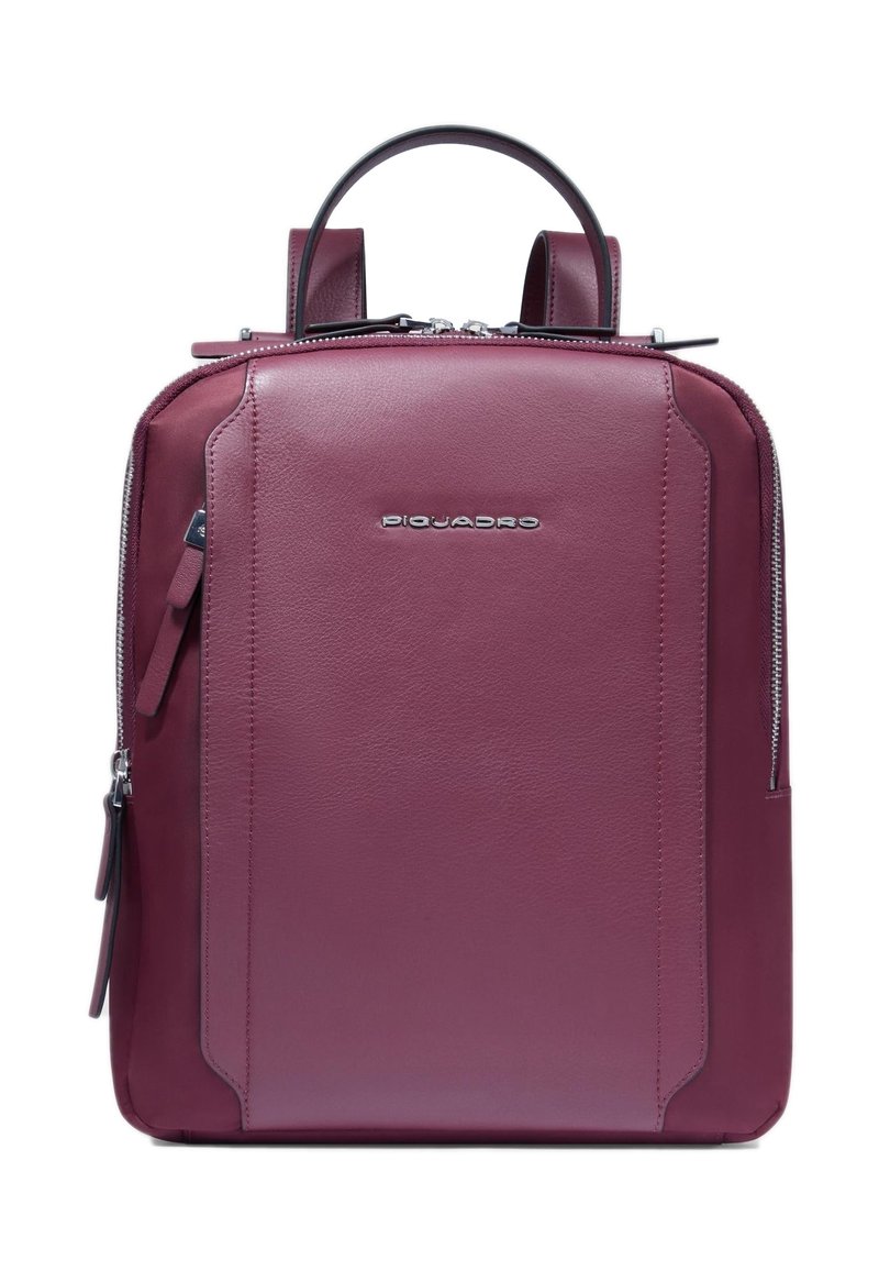 Rucksack aus kastanienbraunem Leder mit klarer Form, zwei Griffen und Reißverschluss. Verfügt über ein dezentes Logo und eine Seitentasche. Glatte Textur.