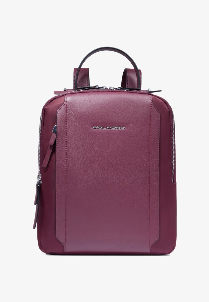 Rucksack aus kastanienbraunem Leder mit klarer Form, zwei Griffen und Reißverschluss. Verfügt über ein dezentes Logo und eine Seitentasche. Glatte Textur.