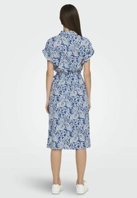 Abito a maniche corte con motivo blu e bianco, vita con cintura, silhouette fino al ginocchio e texture del tessuto liscia.