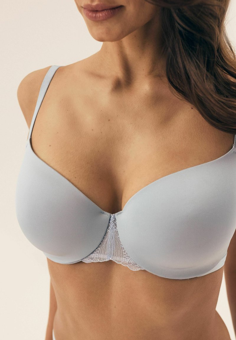 Jasnoniebieski stanik wykonany z gładkiego materiału, z koronkowym detalem na środku. Posiada cienkie, regulowane ramiączka oraz dekolt w szpic.