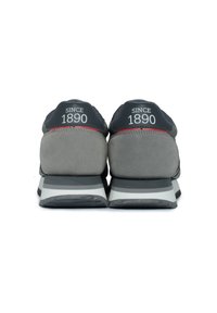 Graue Sneakers mit schwarzen Akzenten, die ein Obermaterial aus Wildleder und Mesh, eine dicke Mittelsohle und die Aufschrift "SINCE 1890" auf der Rückseite aufweisen.