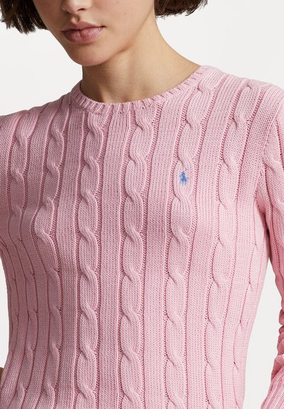 Pull en tricot rose clair au design en câble avec un col rond à côtes et un petit logo bleu sur la poitrine. Motif texturé sur l'ensemble.