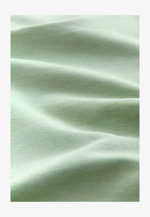 Tessuto verde chiaro con una superficie liscia e leggermente texture, che mostra morbide pieghe fluide e un motivo rigato.