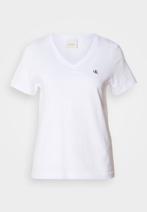 Hvit bomulls t-skjorte med kort erm og V-utringning, med en liten svart "CK" logo på venstre brystområde. Glatt tekstur og klassisk design.