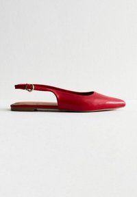Röd lädersandal med flat sula, spetsig tå, öppen häl och ett litet spänne på anklebandet. Slät textur, minimalistisk design.