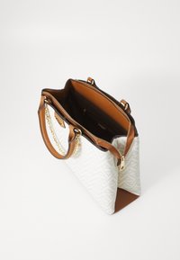 Bolso tote en blanco con un patrón de espiga, acentos de imitación cuero marrón y detalle de cadena dorada. Cierre superior con cremallera, interior espacioso.