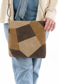 Tan and brown patchwork suede crossbody bag with a geometric design. Features a detachable strap and metal hardware accents. Compact shape.