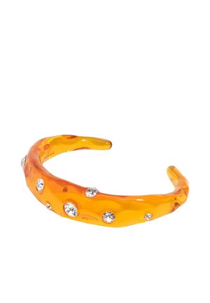 Brazalete rígido de resina translúcida naranja con cristales redondos y transparentes incrustados, diseño abierto.