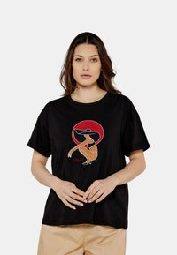 T-shirt nera a maniche corte con un grafiche colorato di una donna con un grande cappello su uno sfondo di cerchio rosso. Materiale in cotone, vestibilità comoda.