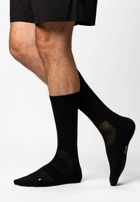 Calzini sportivi neri con texture a coste, dotati di pannelli in rete per la traspirabilità e suole rinforzate. Lunghezza standard, design elegante.
