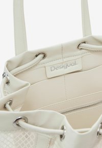 Borsa a tote bianca in pelle con superficie liscia, hardware in argento e un accento in rete. Presenta un compartimento con zip e un logo stampato.
