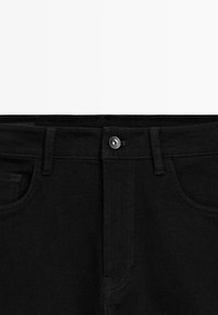 Zwarte denim jeans met een sluiting met knoop aan de voorkant, riemlussen en twee frontzakken. Kenmerkt zich door contrasterende stiksels en een soepele textuur.
