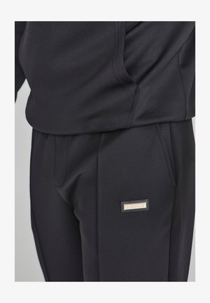 Svarta sportbyxor i smidigt tyg med slim fit. Har sidfickor och en metalllogotyp på vänster sida.