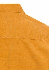 Kordhemd in goldenem Orange mit strukturiertem Oberflächenmaterial und umgeschlagenem Kragen. Rückansicht mit sichtbaren Nähdetails.