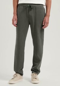 Mørk grønn, lette joggers med elastisk midje og justerbar snøring. Glatt tekstur, tapered passform, sidelommer og minimalistisk design.