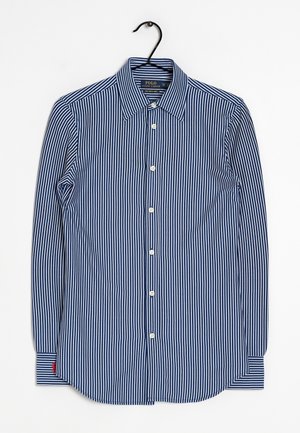 Marinblå och vitrandig långärmad skjorta med knappar och krage, med vita knappar och en röd detalj på vänster ärmslut.