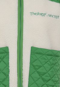 Chaqueta de forro polar con cuerpo crema y acentos acolchados verdes. Cuenta con una cremallera frontal y dos solapas de bolsillo. Logo bordado en el pecho.