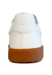 Sneaker bianco con suola in gomma texturizzata, caratterizzata da un materiale superiore liscio e da un "BACK 70" in rilievo sul tallone. Forma arrotondata, design minimal.