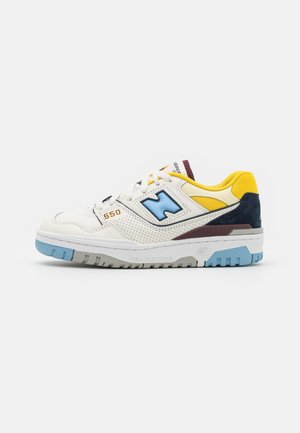 Baskets blanches New Balance 550 avec des accents bleus, jaunes et bordeaux, semelle bleu clair et panneaux latéraux perforés.
