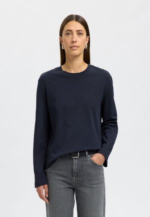 Marineblauwe longsleeve t-shirt van katoen, met een ronde hals en een ontspannen pasvorm. Gecombineerd met grijze jeans. Eenvoudig ontwerp, geen patronen.