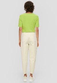 Groene short-sleeve shirt met een ronde hals, gecombineerd met beige tapered cargobroek. De schoenen zijn off-white en hebben een dikke zool.