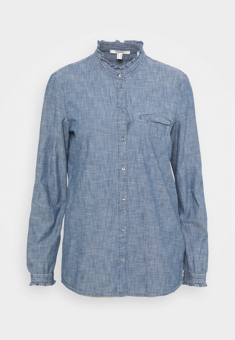 Blouse chambray bleu clair à manches longues avec col haut volanté, fermeture à boutons sur le devant, poche poitrine unique avec rabat et poignets volantés.