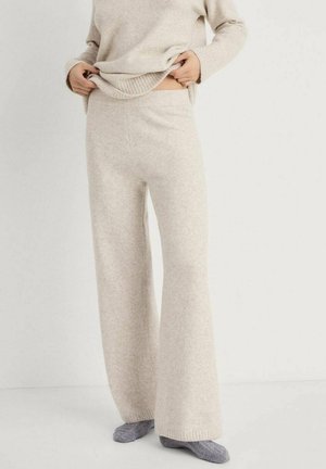 Helle beige, weit geschnittene Strickhosen mit weicher Textur und geripptem Bund, getragen mit einem übergroßen, passenden Pullover und grauen Socken.