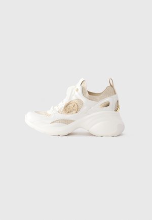 Sneaker a maglia bianca e beige con suola chunky, lacci anteriori, logo del marchio sul lato e linguetta sul tallone su sfondo uniforme.