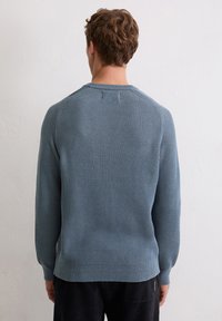 Lichtblauwe gebreide trui met een textuurpatroon, ronde halslijn en lange mouwen, voorzien van een zijtag-detail.