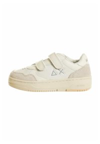Sneaker bianco con accenti in suede, dotata di due cinturini in Velcro, perforazioni circolari e una suola in gomma testurizzata. Logo visibile sul lato.