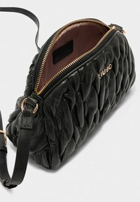Geantă crossbody din piele quilted neagră cu închidere cu fermoar aurit, interior spațios și curea ajustabilă. Textură netedă cu cusături evidente.