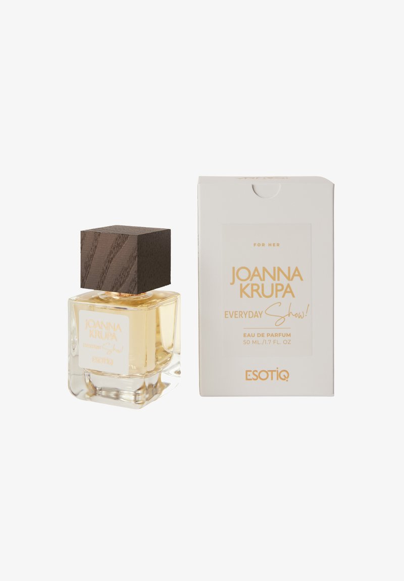 Przezroczysta szklana butelka perfum z brązową, kwadratową nakrętką, wypełniona jasnofioletowym płynem. Pudełko ma wyraźny tekst w kolorze złotym i białym, oznaczone "Dla Niej."