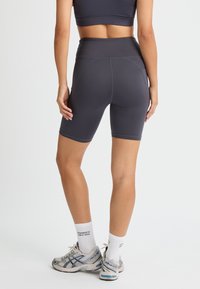 Höga, mörkgrå träningsshorts i ett mjukt, elastiskt tyg, med sömdetaljer och en åtsittande siluett.