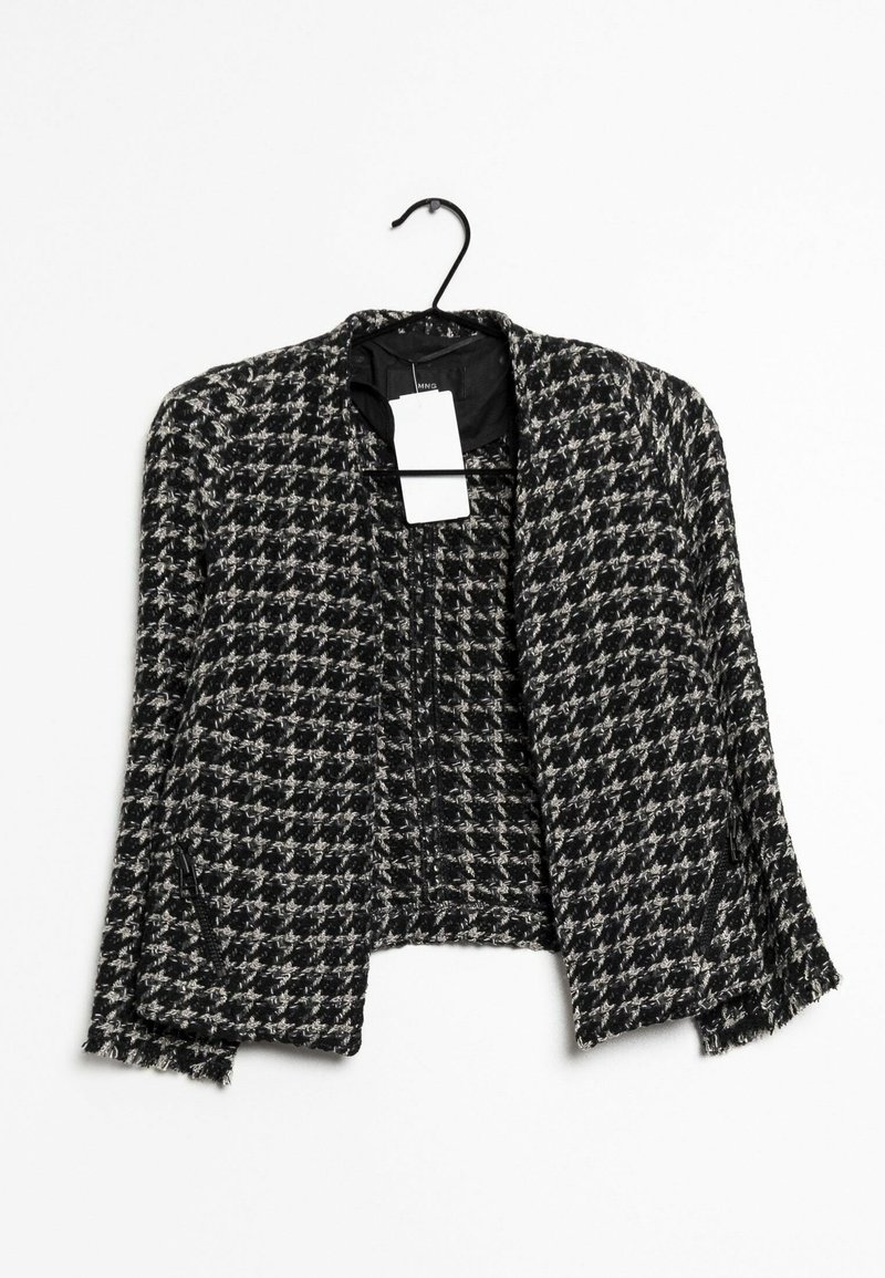 Czarna i biała kurtka typu blazer o kroju cropped w deseń houndstooth, bez kołnierza, z zamykanymi kieszeniami i zwisającą etykietą. Teksturowana tkanina.