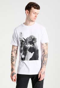 Hvid bomulds T-shirt med et sort-hvidt grafisk motiv af en mand med bandana, teksten lyder "TUPAC." Kortærmet, rund hals design.