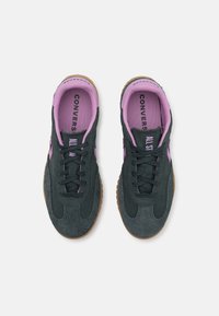 Baskets en daim gris avec accents roses et lacets noirs. Semelle en caoutchouc gomme circulaire. Texte « CONVERSE » et « ALL STAR » sur les semelles intérieures.