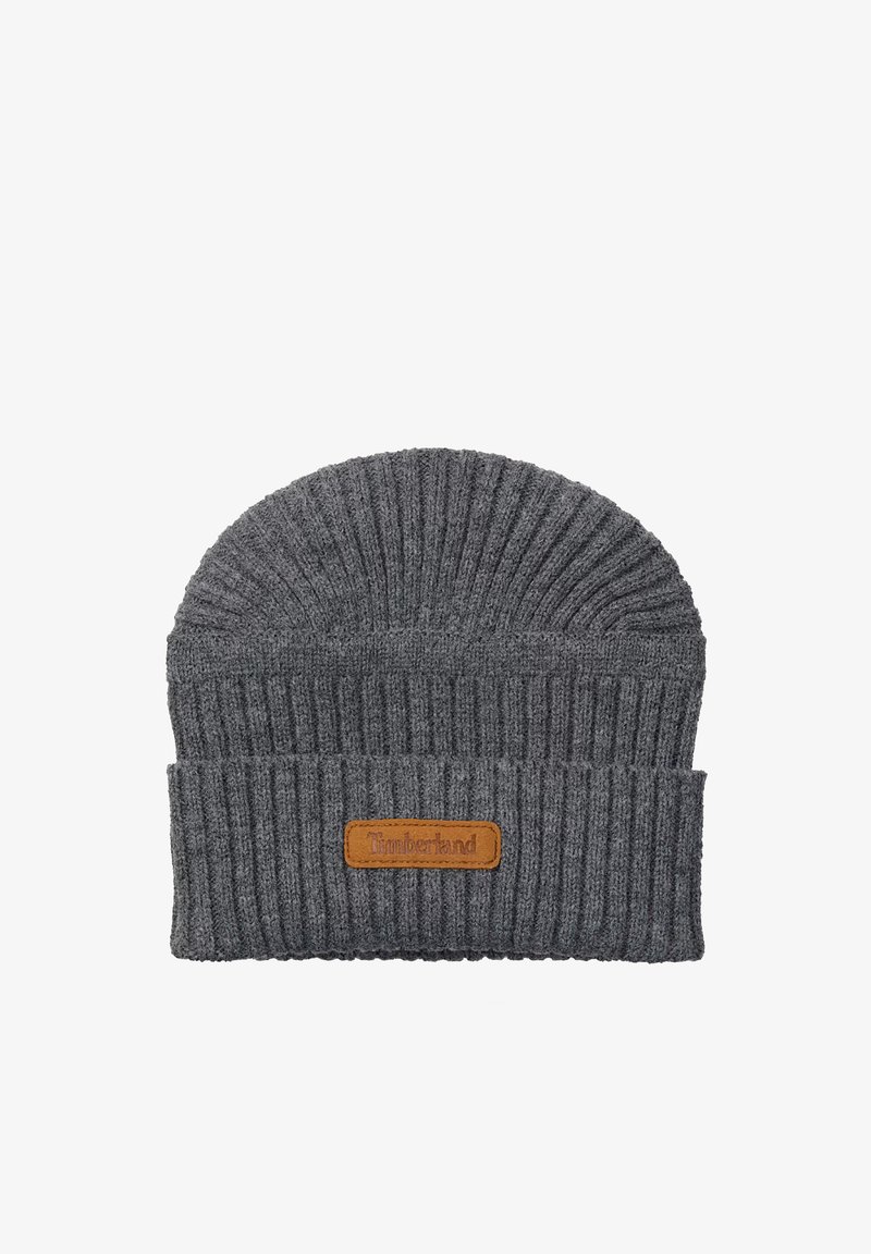 Cappello grigio lavorato a maglia con una spessa texture a coste. Presenta una toppa in pelle marrone con il logo "Timberland" sul risvolto piegato.