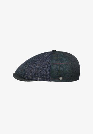 Flat cap with patchwork design in various dark blue and grey tweed patterns, featuring a small round metallic logo on the side.