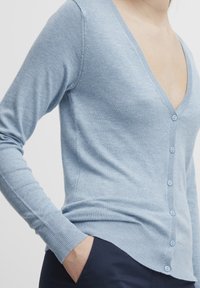 Cardigan bleu clair en tissu tricoté doux avec un décolleté en V profond, des manches longues complètes et cinq boutons assortis sur le devant.