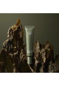 Vihreä BB-voideputkilo, jossa on SPF 20, kohokuvioitu teksti ja kapeneva kansi, asetettuna teksturoidun luonnonpuun taustalle.