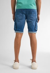 Farkku cargo shorts vaaleansinisinä, joissa on käännetyt lahkeet ja sivutaskut. Suunnittelussa on takataskut ja normaali istuvuus.