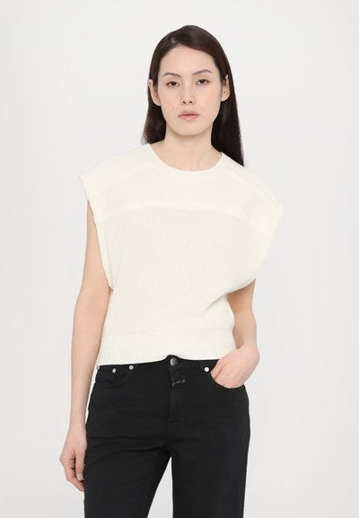 Hvit, ribbestrikket ermeløs topp med rund halsutskjæring og avslappet passform, kombinert med svarte slim-fit jeans.