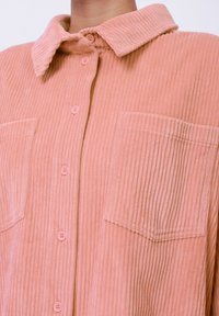 Roze corduroy button-up shirt met een kraag, twee voorzakken en een gestructureerde ribbelstof. Heeft bijpassende knopen.