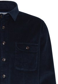 Camisa de pana azul marino con estrías verticales, botones frontales y un bolsillo en el pecho. Presenta un cuello extendido y una tela texturizada.