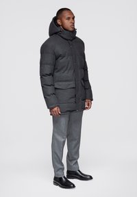 Grå vadderad jacka med huva, utrustad med knappstängning, framfickor och texturerat tyg, kombinerad med grå byxor och svarta ankelboots.