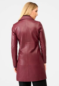 Burgundy leather coat with a sleek design, featuring long sleeves, a notched collar, and a mid-length silhouette. Smooth texture, minimalist style.