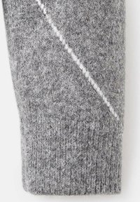 Manga de suéter de punto gris con una textura acanalada y un patrón de costura blanca diagonal para darle detalle. Tela suave y gruesa.