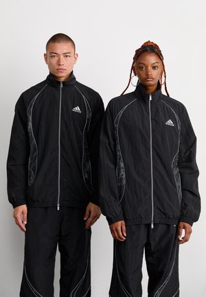 Svarta zip-up-jackor med kontrasterande silveraccenter och sidomönster, parat med matchande byxor; tillverkade av lättviktsmaterial.