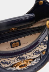 Marine læderhåndtaske med et mønstret interiør, guldhardware, lynlåslomme og et logomærke, som understreger et struktureret design.