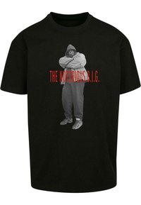Black t-shirt featuring a gray graphic of a person in a hooded jacket, arms crossed, with "THE NOTORIOUS B.I.G." in red text below.